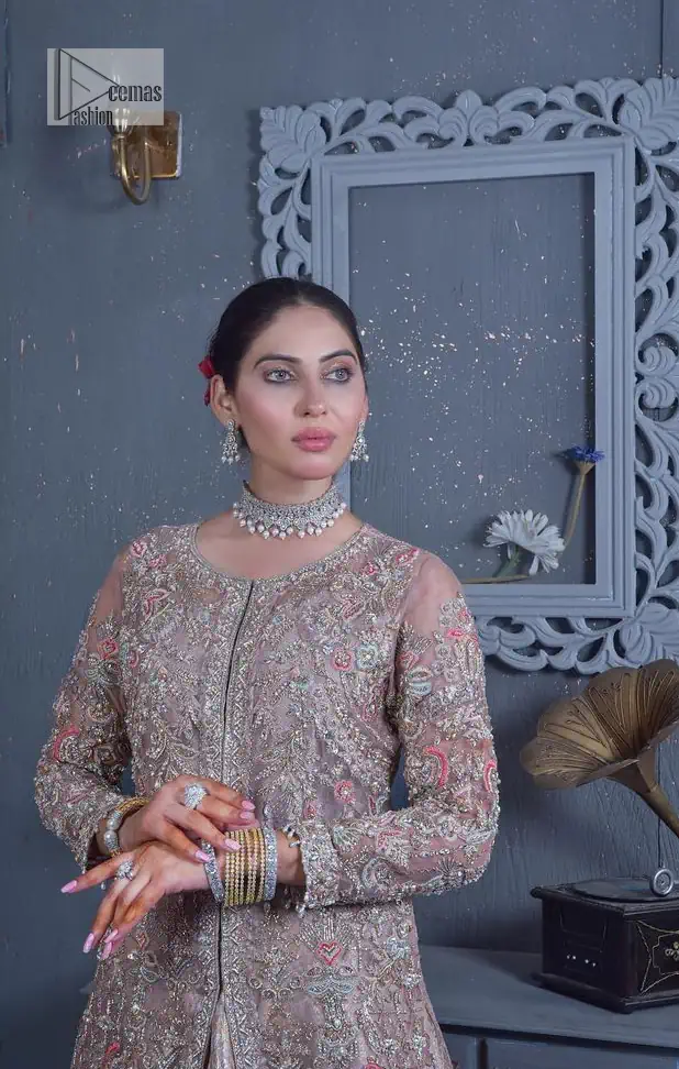 Get cosy in a tea rose nikah outfit. DeemasFashion presents this tea rose front open gown which is heavily embroidered in multiple colours and then further enhanced with the heavy embellishment of tilla, dabka, kora, Kundan and Zardozi making it a perfect fit for brides. The stones touch-up on the round neckline increases the look of the beautiful gown. Furthermore, the full sleeves style of the following gown makes this masterpiece stunning and stylish. It is paired up with flared lehenga in the same colour to balance the overall look of this magnificent attire. Finish this with a dupatta having four-sided borders that gives an everlasting impact on the bride.