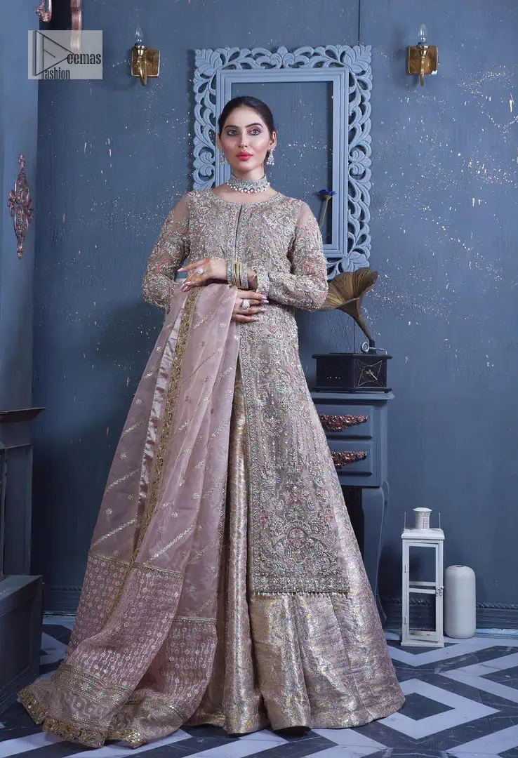 Get cosy in a tea rose nikah outfit. DeemasFashion presents this tea rose front open gown which is heavily embroidered in multiple colours and then further enhanced with the heavy embellishment of tilla, dabka, kora, Kundan and Zardozi making it a perfect fit for brides. The stones touch-up on the round neckline increases the look of the beautiful gown. Furthermore, the full sleeves style of the following gown makes this masterpiece stunning and stylish. It is paired up with flared lehenga in the same colour to balance the overall look of this magnificent attire. Finish this with a dupatta having four-sided borders that gives an everlasting impact on the bride.