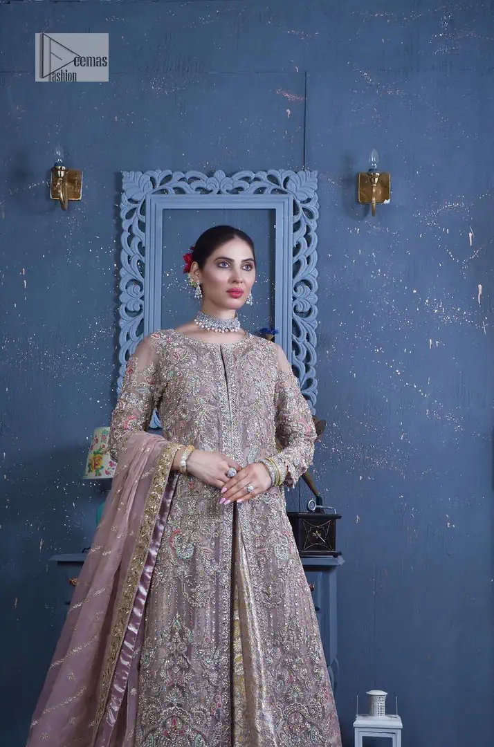 Get cosy in a tea rose nikah outfit. DeemasFashion presents this tea rose front open gown which is heavily embroidered in multiple colours and then further enhanced with the heavy embellishment of tilla, dabka, kora, Kundan and Zardozi making it a perfect fit for brides. The stones touch-up on the round neckline increases the look of the beautiful gown. Furthermore, the full sleeves style of the following gown makes this masterpiece stunning and stylish. It is paired up with flared lehenga in the same colour to balance the overall look of this magnificent attire. Finish this with a dupatta having four-sided borders that gives an everlasting impact on the bride.