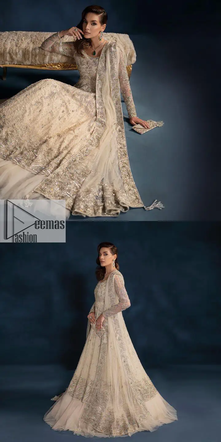 A sophisticated splash of off-white as your nikah outfit! With its round neckline and full sleeves, this outfit has a fine fusion look. Utilizing attractive silver embellishment work to enhance its intricate beauty. Tilla, dabka, kora, Kundan and the details of Zardozi beautifully embellish the elegant frock. It is paired with a flared lehenga to balance the overall look of this charming article. Finish this soft and bold look with a heavily bordered four-sided dupatta with a spray of sequins all over to make your Big day super aesthetic.